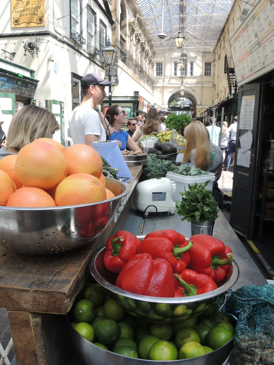 Fruits et légumes au premier plan d’un étal sous la verrière de St Nicholas Market.
